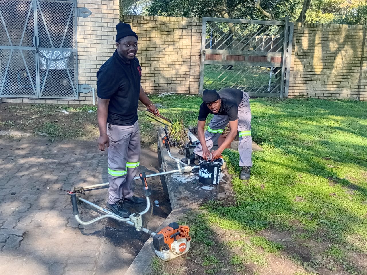 Two team members with brush cutting equipment on site