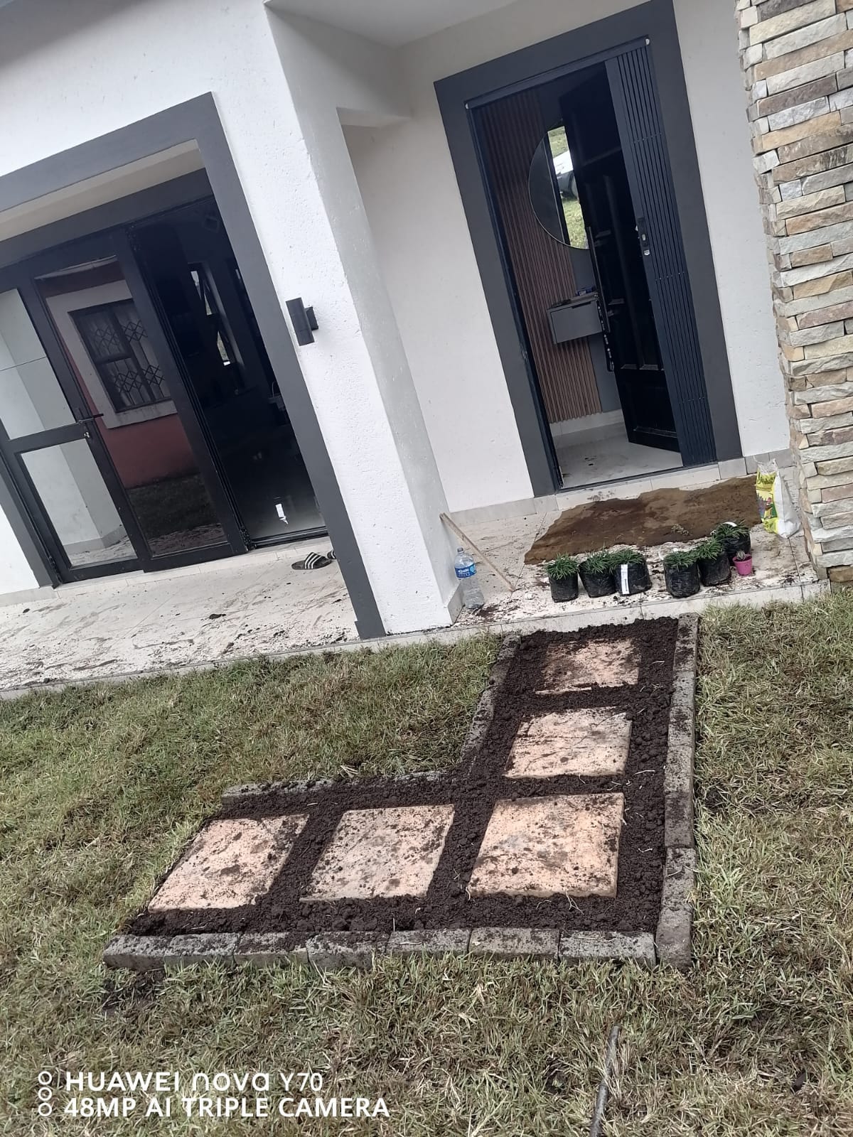 Newly built stepping-stone pathway with fresh soil and edging beside a home entrance