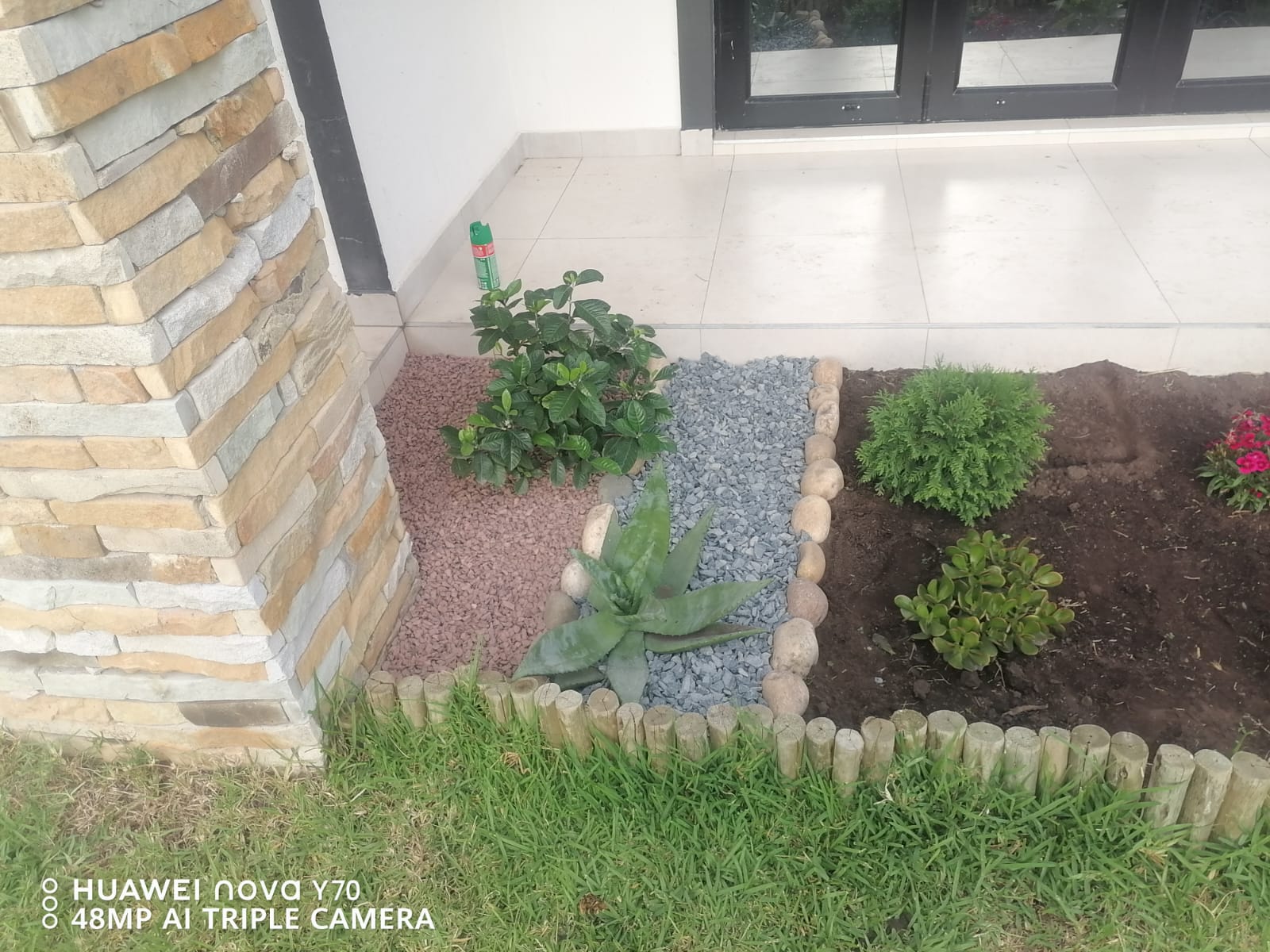 Decorative stone garden bed with pink and grey gravel, shrubs and log edging