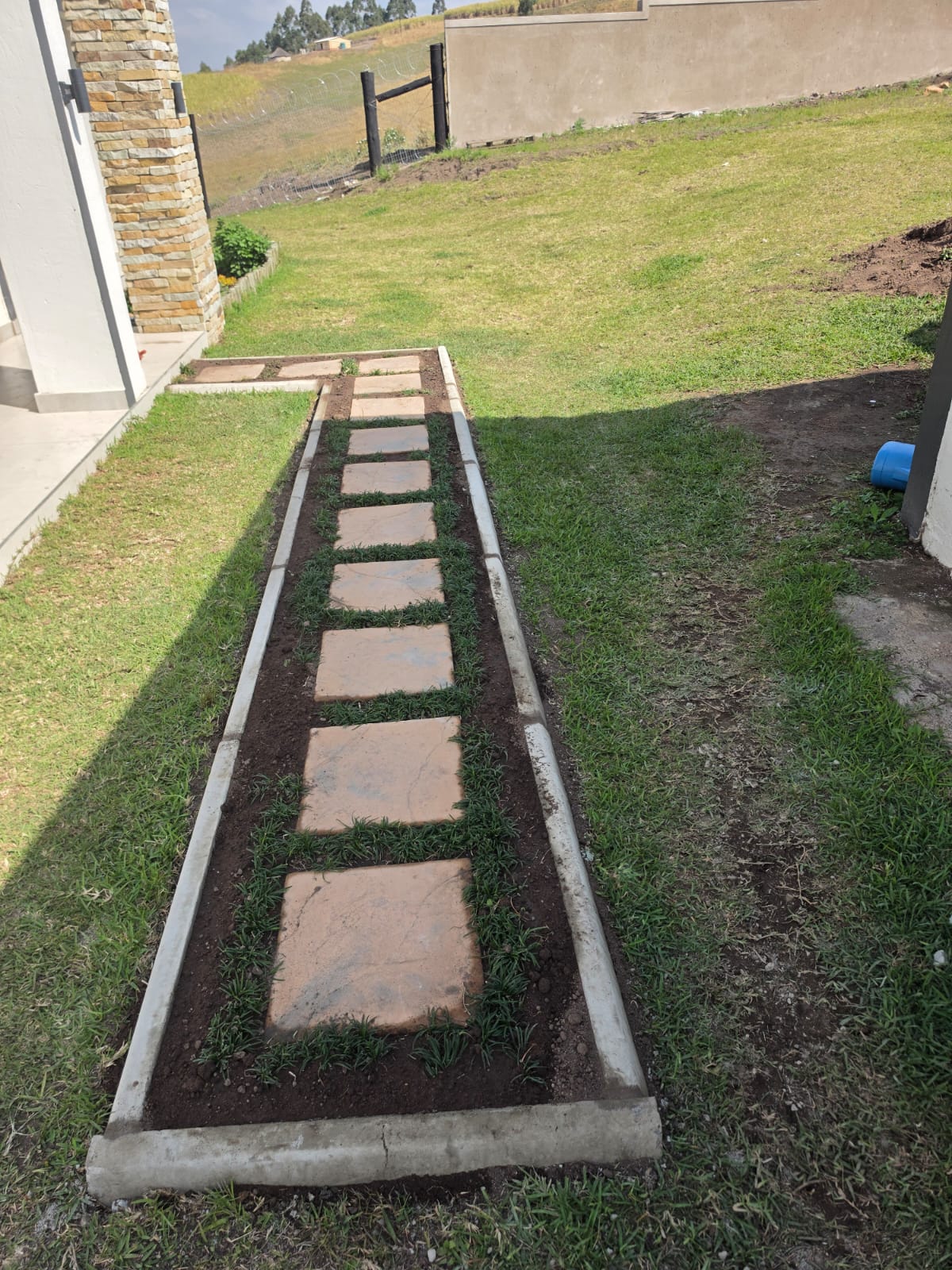 Paved stepping-stone walkway set into a lawn with concrete kerb edging