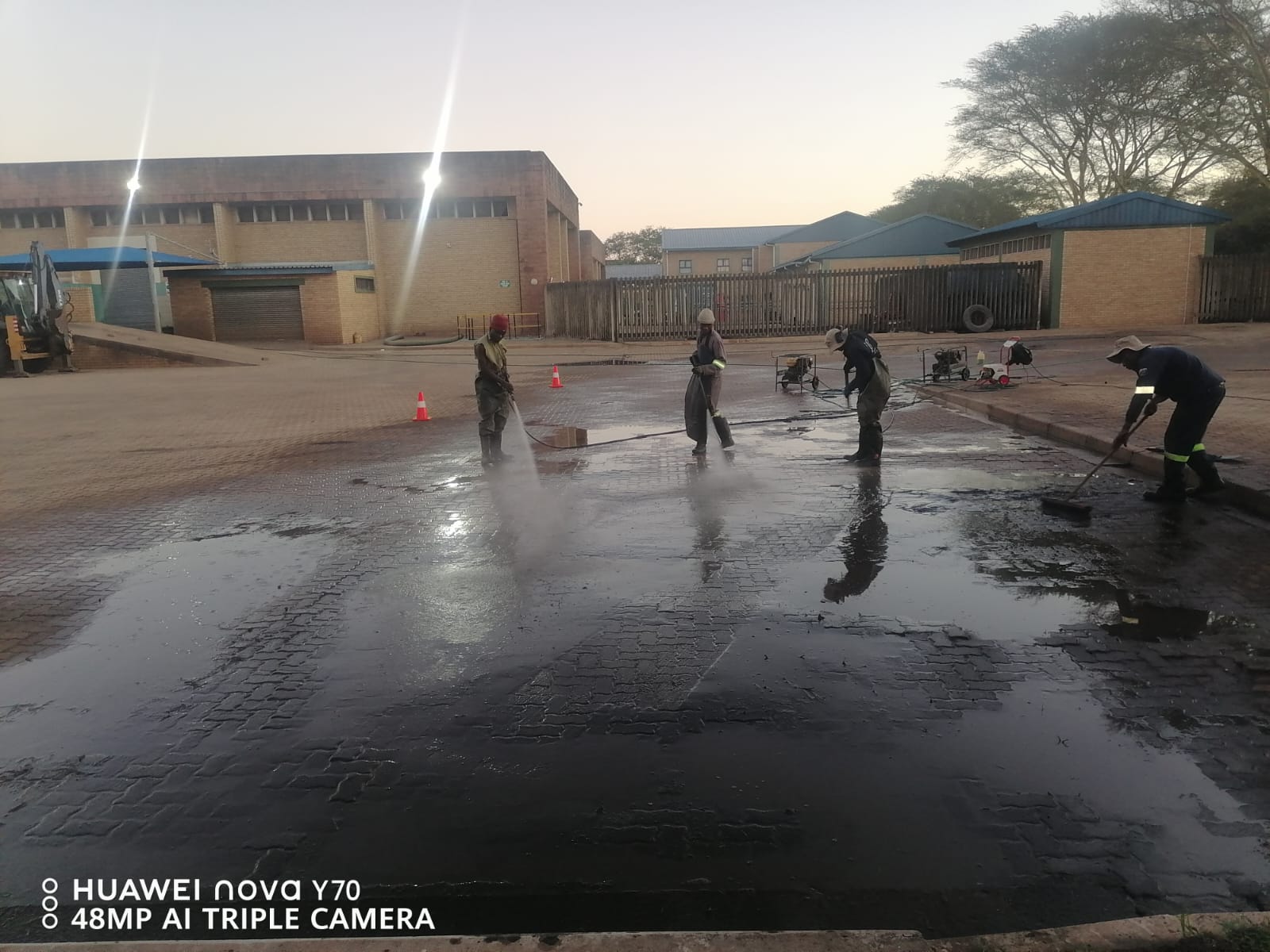 Crew high-pressure cleaning a paved outdoor surface