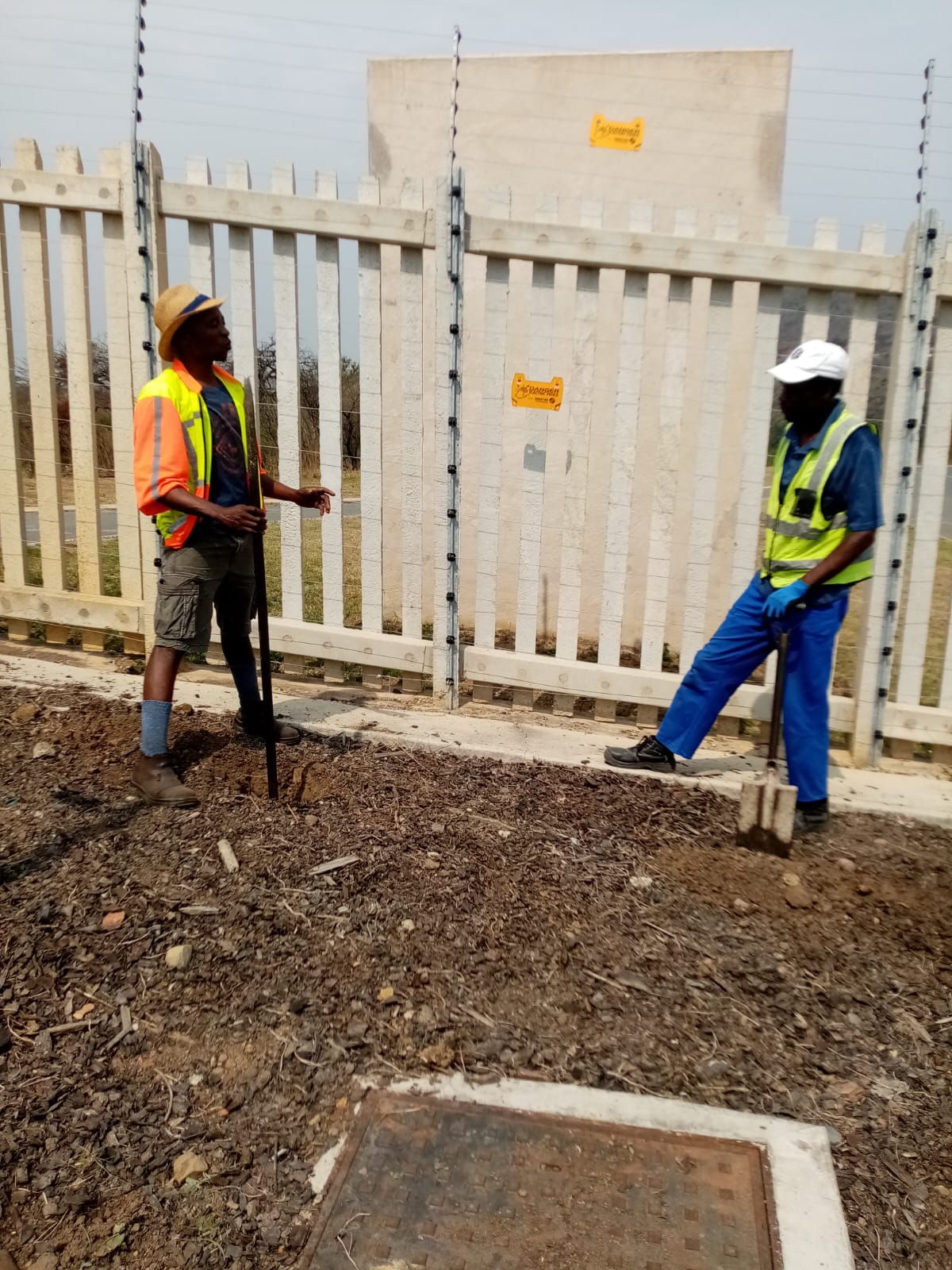 Two team members on site beside a property fence line