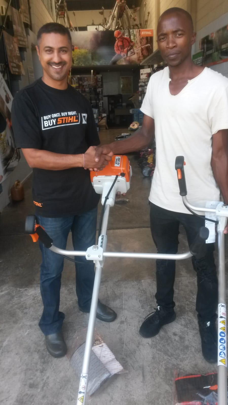 Team members shaking hands beside brush cutting equipment