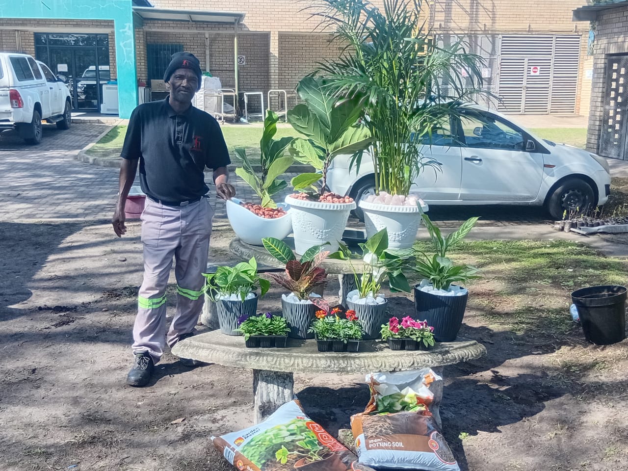 Team member standing beside a display of potted plants, planters and potting soil